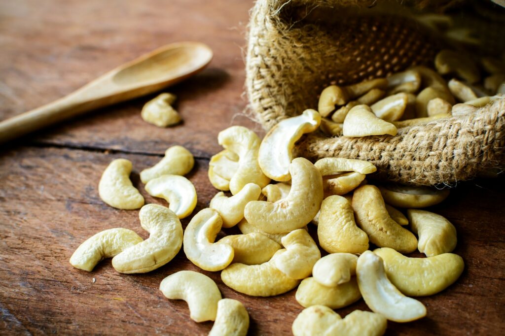 Cashew nuts with wooden spoon on old wood textured